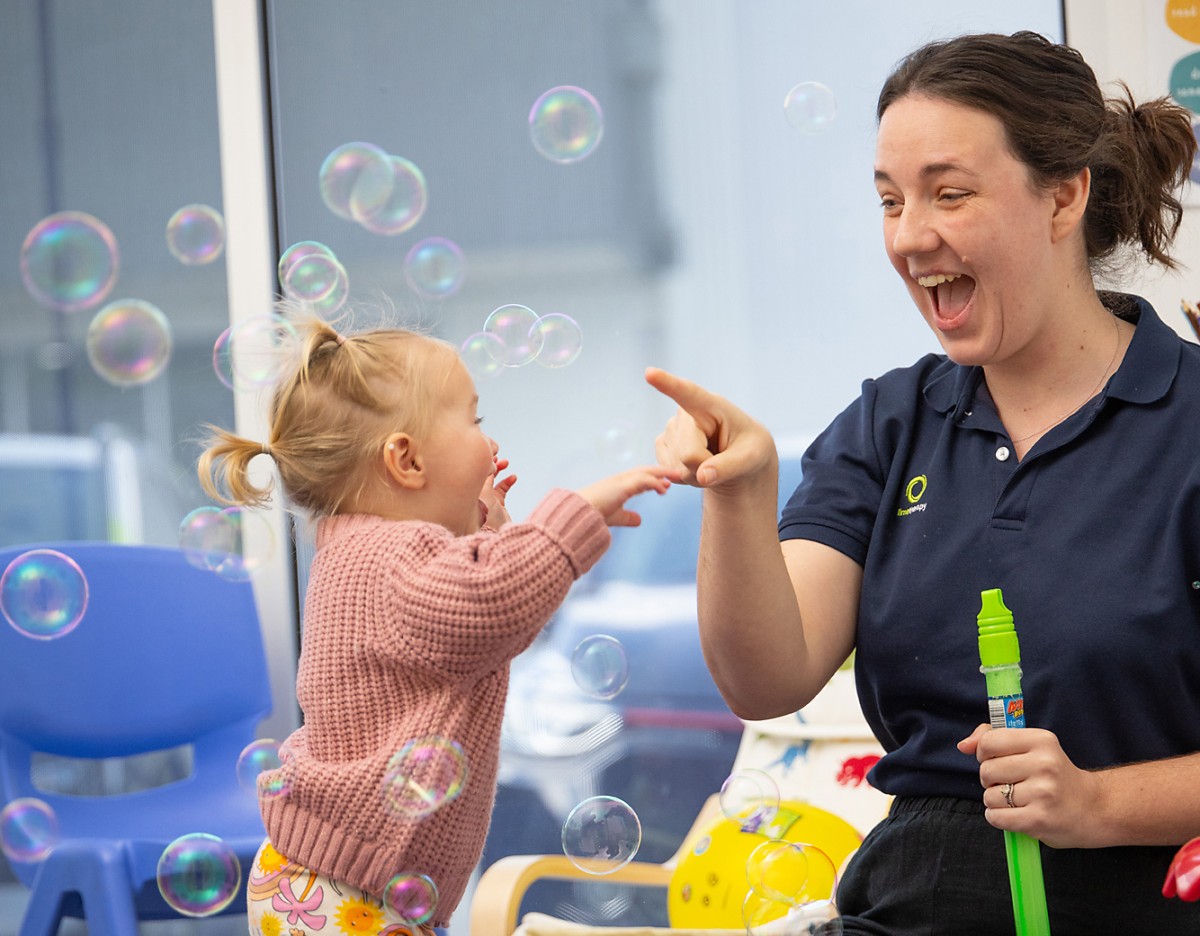 Photo of speech therapist Addie, blowing bubbles for a small client.